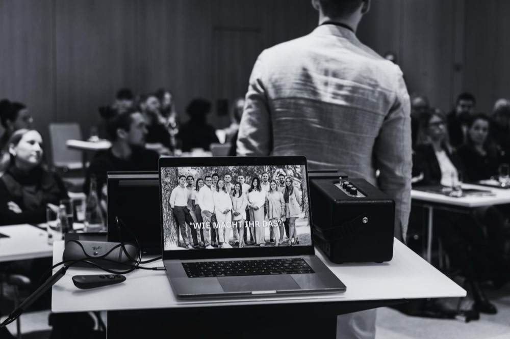 Vortrag vor vollem Saal, im Vordergrund ein Laptop am Pult